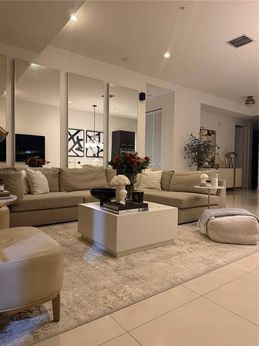 Living area featuring floor-to-ceiling wall mirrors, recessed lighting, and large-format tile flooring