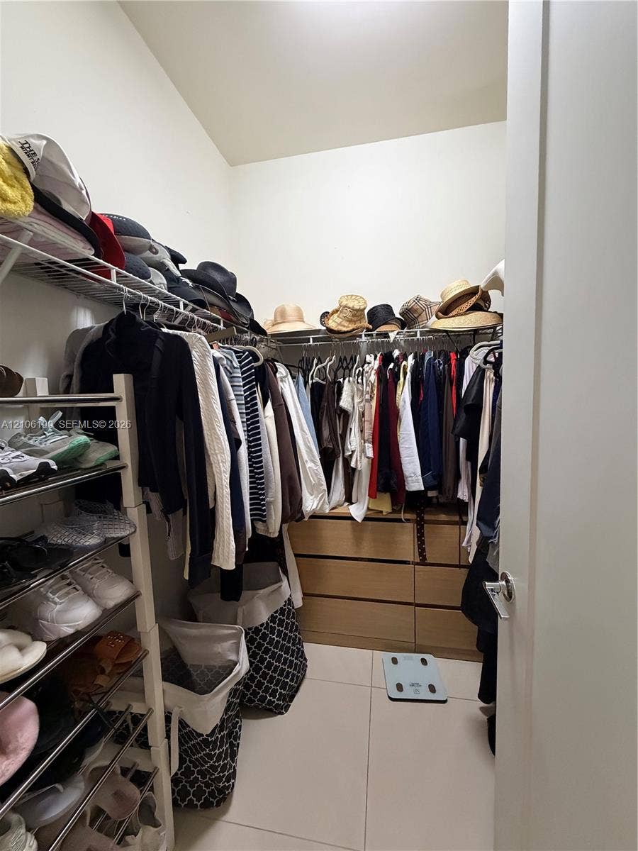 Walk-in closet featuring light-toned cabinetry with six pull-out drawers, white tile flooring, and integrated metal wire shelving