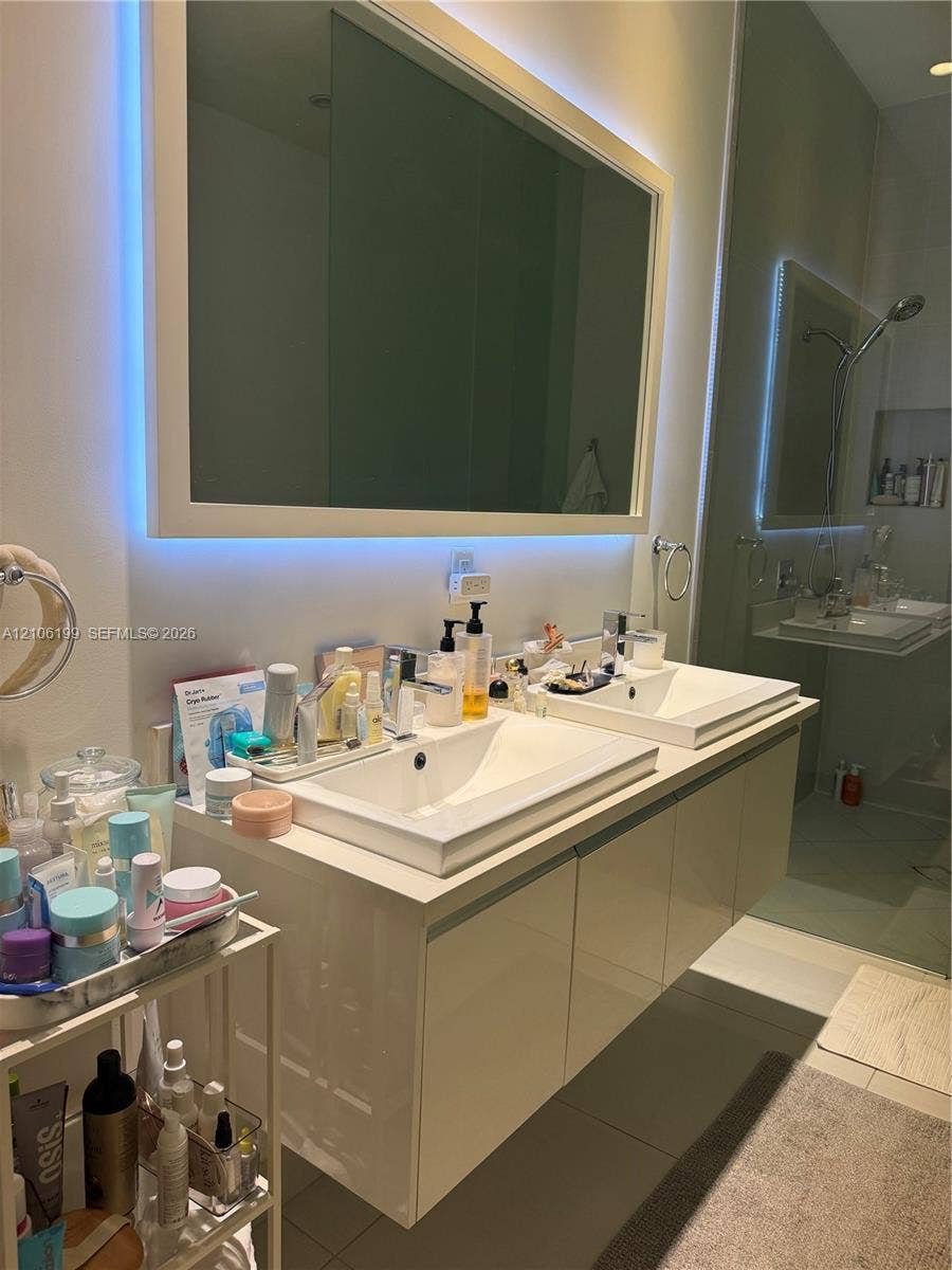 Floating dual-sink vanity with high-gloss cabinetry, square vessel sinks, integrated LED-backlit mirror, and polished chrome fixtures