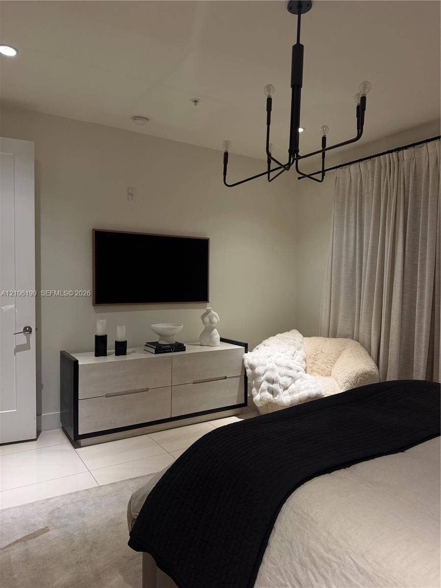 Modern matte black chandelier, large-format tile flooring, and clean-lined solid door