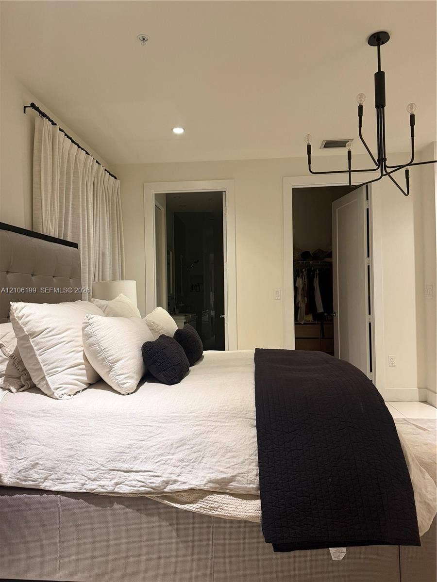 Minimalist space featuring a matte black multi-arm chandelier, recessed ceiling lighting, and smooth-finish flooring