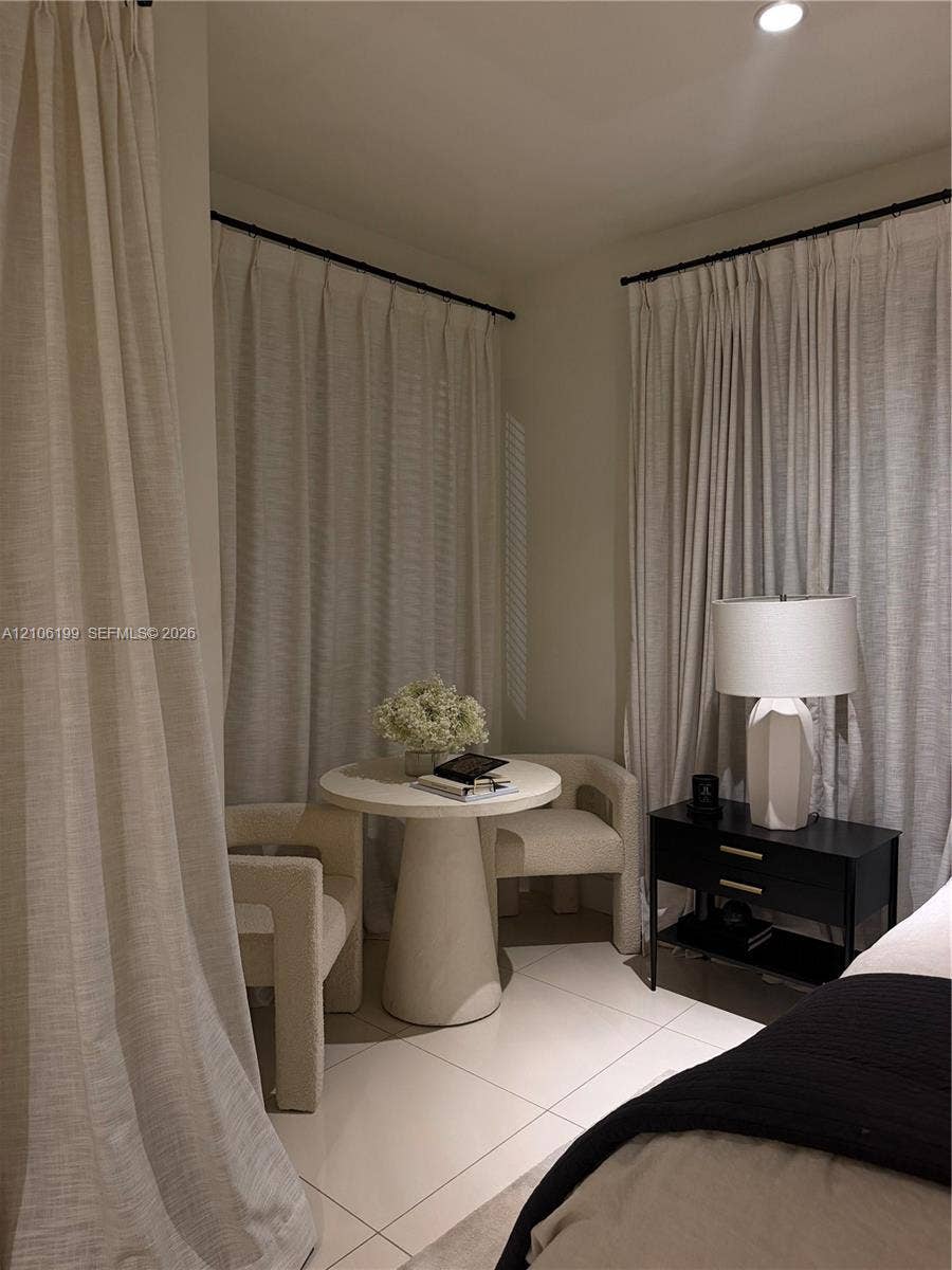 Neutral-toned tile flooring, corner window configuration with floor-to-ceiling drapery, and recessed lighting