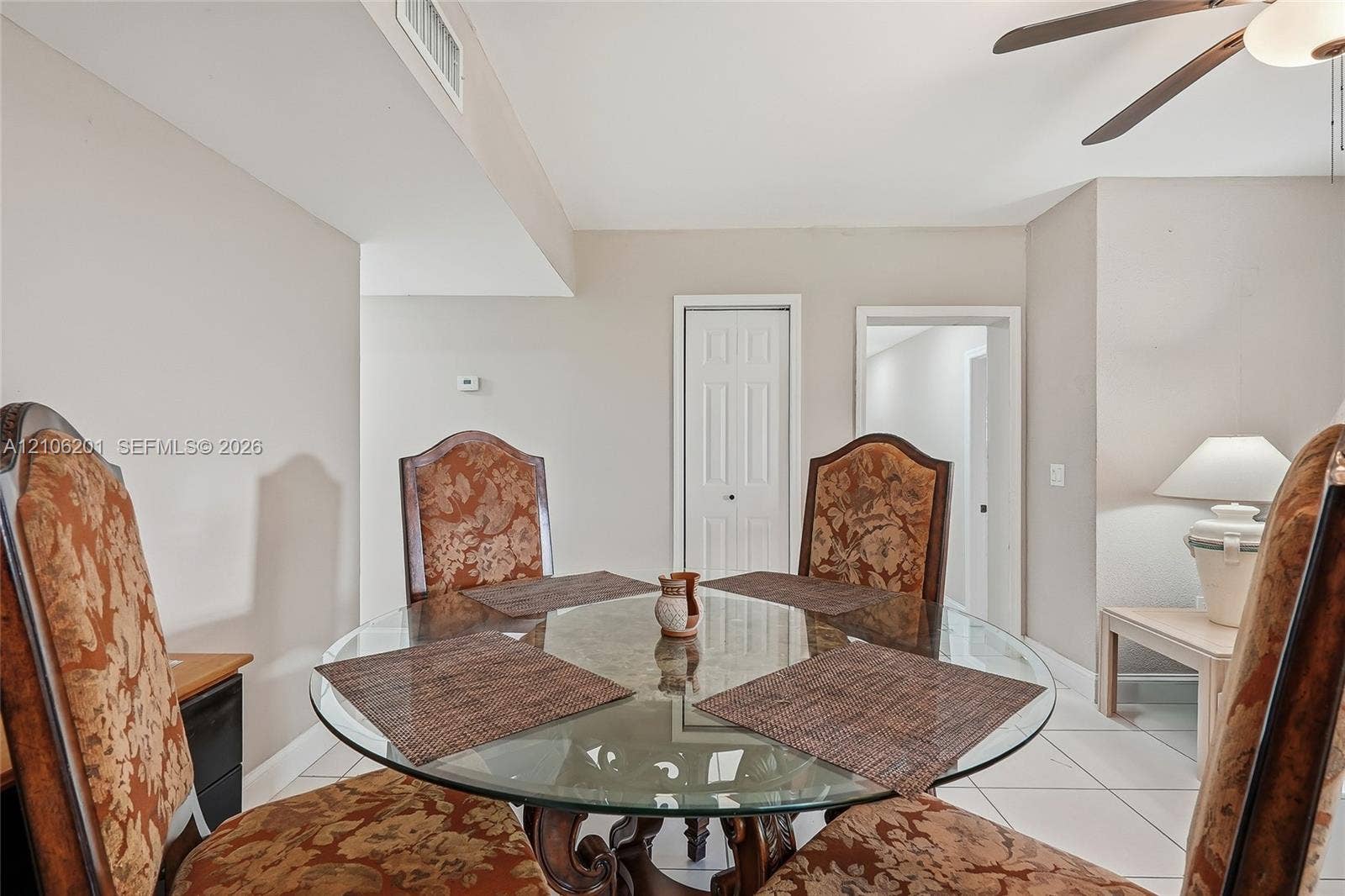 Neutral interior featuring white tile flooring, six-panel interior doors, and a ceiling-mounted fan with integrated light fixture