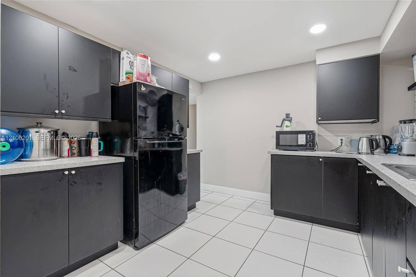 Kitchen featuring matte black cabinetry, light-toned composite countertops, white ceramic tile flooring, and recessed ceiling lighting