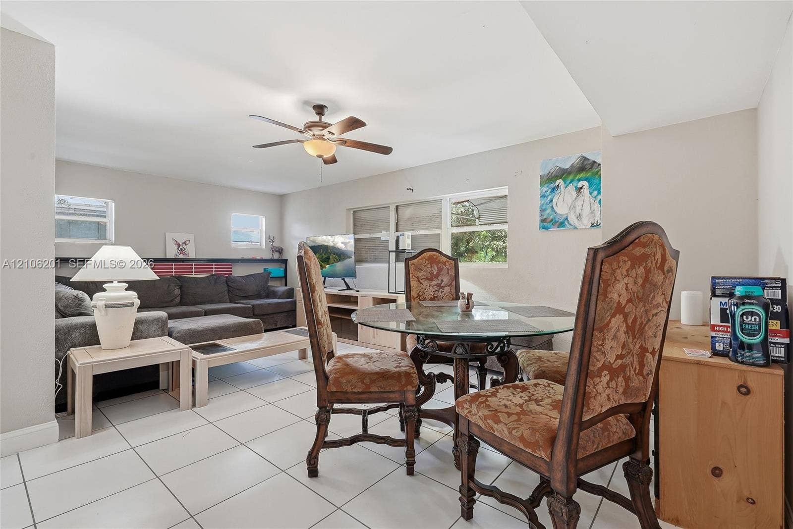 Open-concept interior featuring neutral wall tones, large-format tile flooring, and a ceiling fan with integrated light fixture