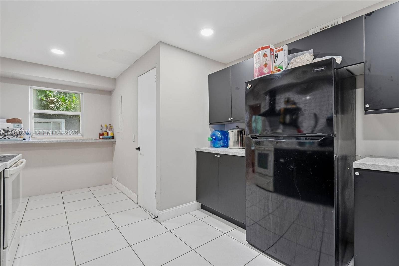 Kitchen featuring dark cabinetry, solid-surface countertops, tile flooring, recessed lighting, and a window ledge