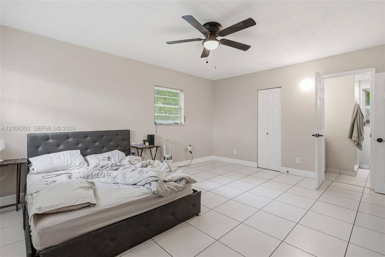 Neutral-toned room featuring large-format tile flooring, a centered ceiling fan with integrated lighting, and a dual-panel closet door