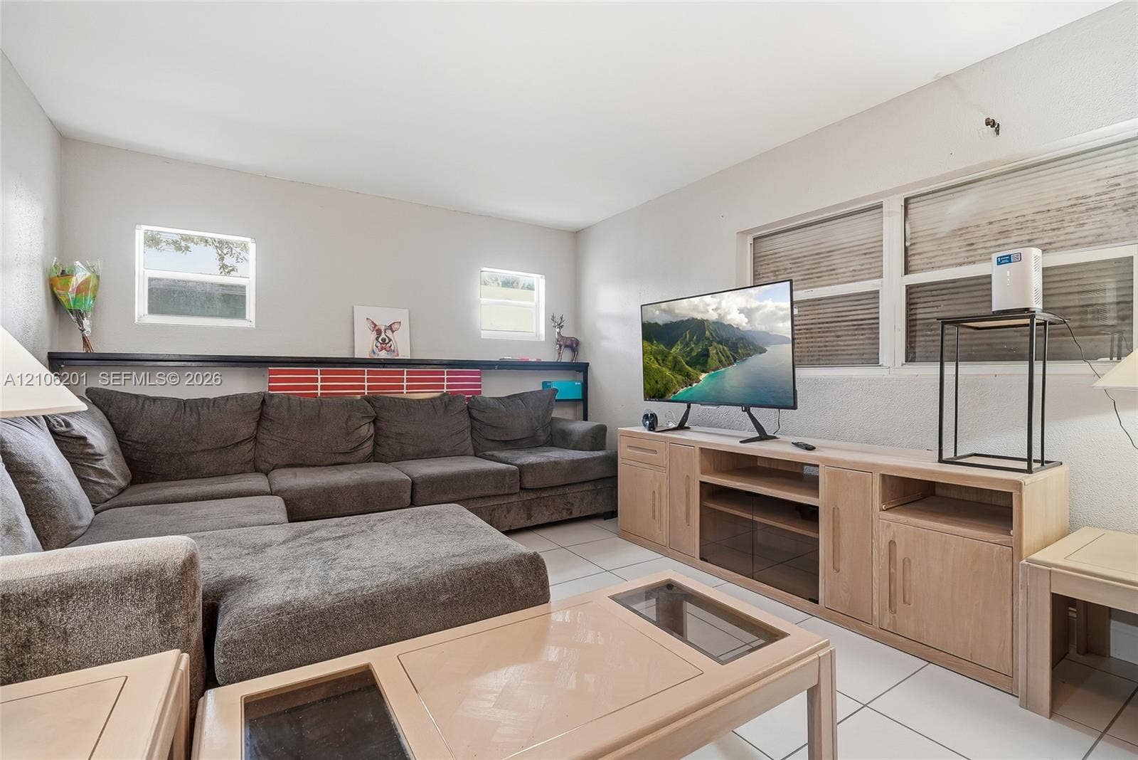 Living area featuring neutral wall paint, tile flooring, and multiple horizontal windows