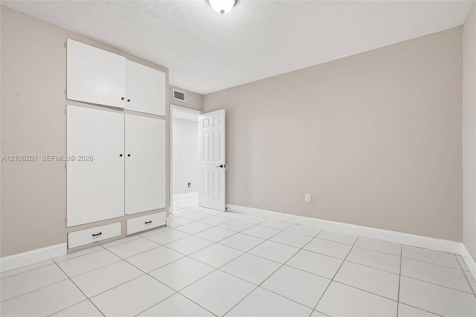 Interior space featuring white floor tiles, neutral wall paint, and floor-to-ceiling built-in white cabinetry with integrated drawers