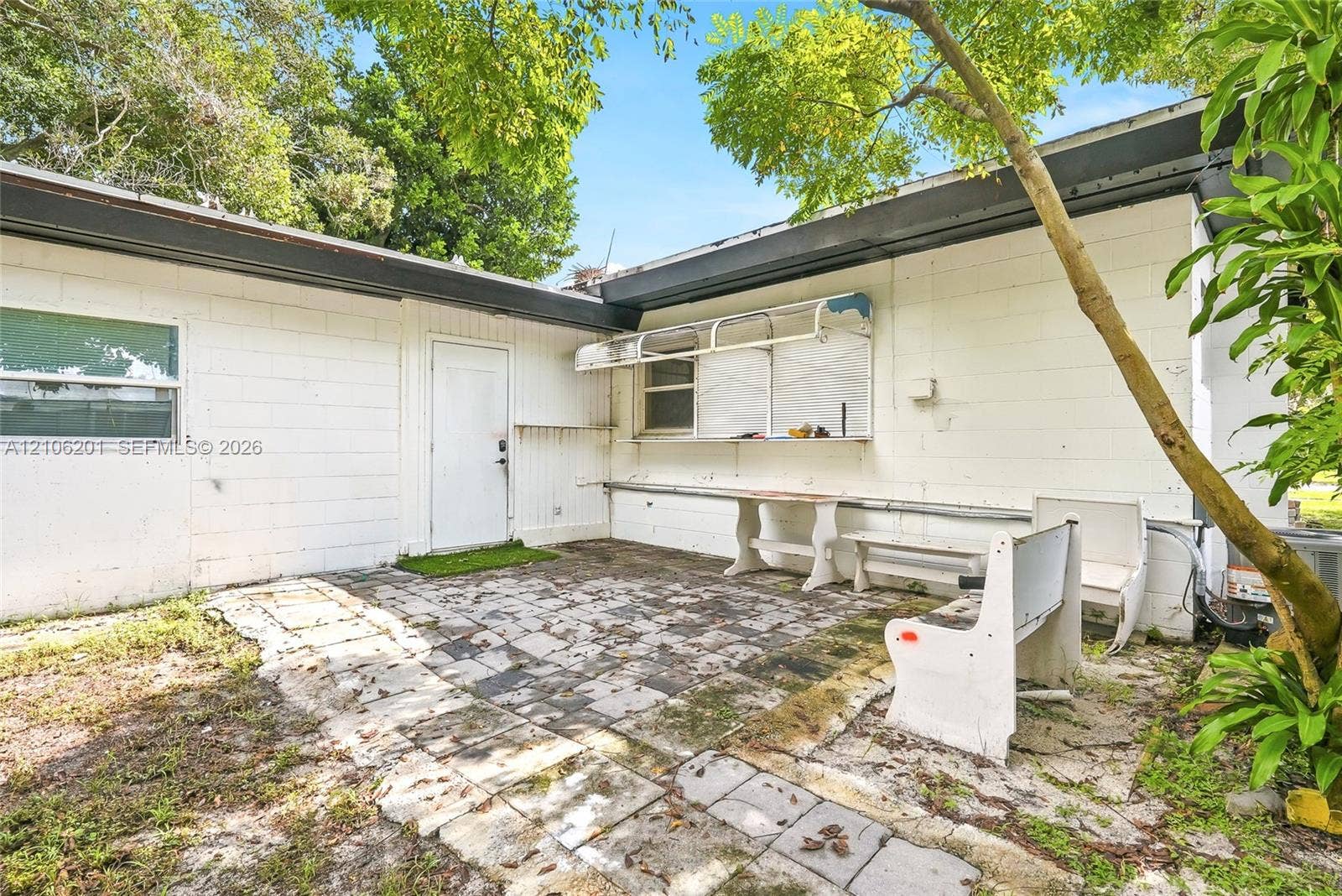 Concrete block exterior featuring a paved patio, metal awning, and built-in serving counter