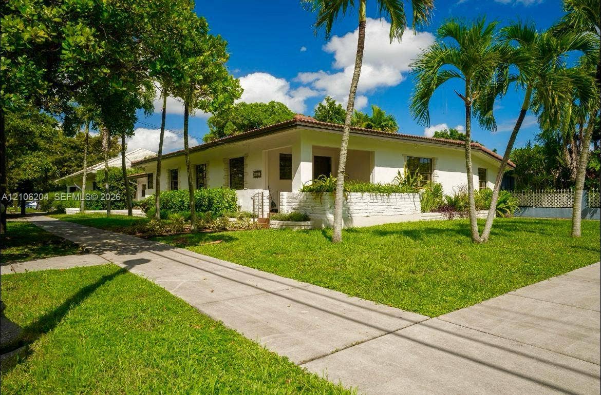 2121 SW 13th Avenue, #Studio, Miami, Miami, FL 33145 Single-story residence featuring a painted brick facade, a covered front entry, low-profile tiled roofing, and a manicured lawn with mature palm trees