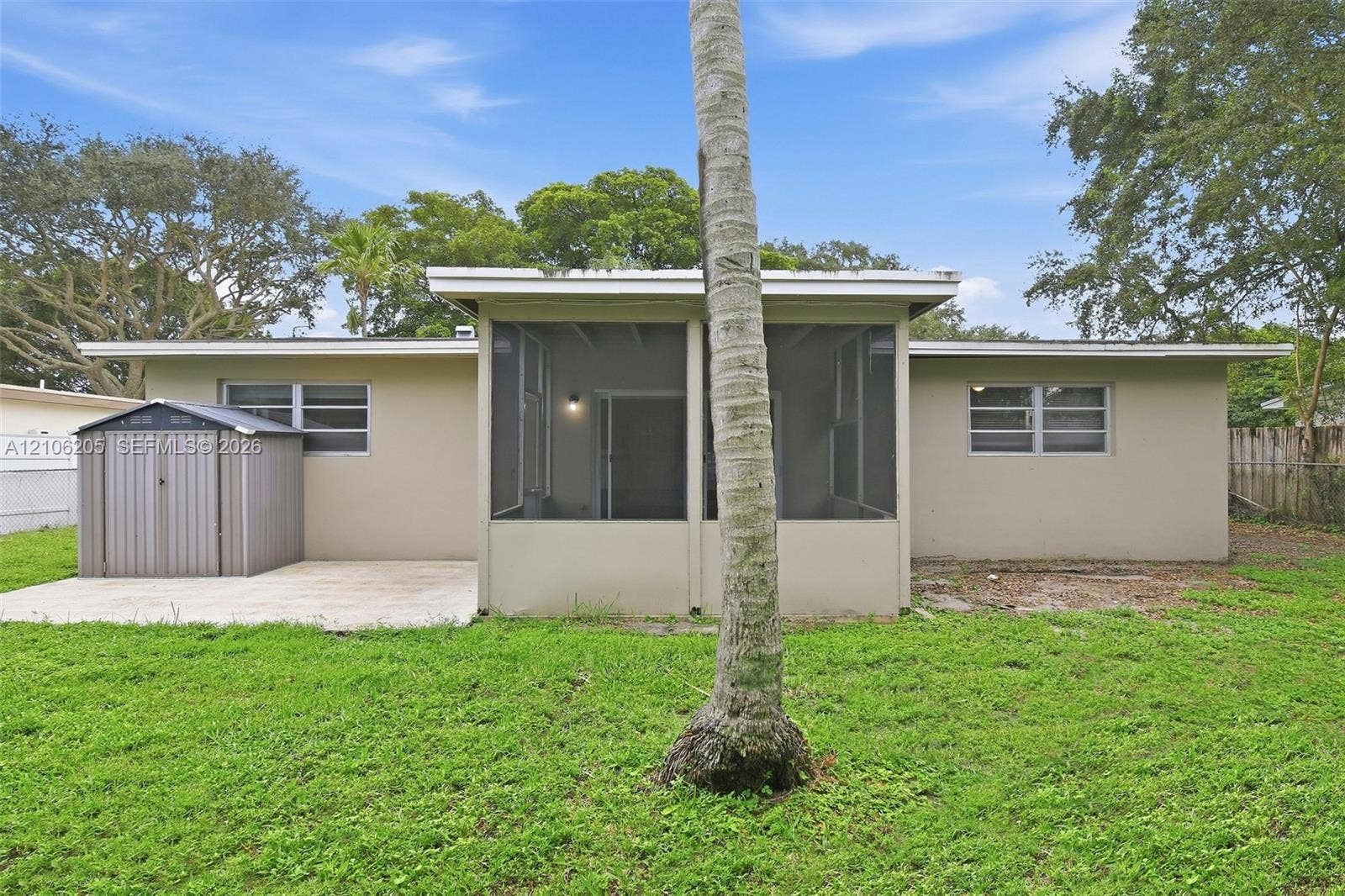 6941 SW 5th Street, Pembroke Pines, Pembroke Pines, FL 33023 Exterior rear elevation featuring a screened-in lanai, concrete patio, and detached metal storage structure situated on a grass-covered lot