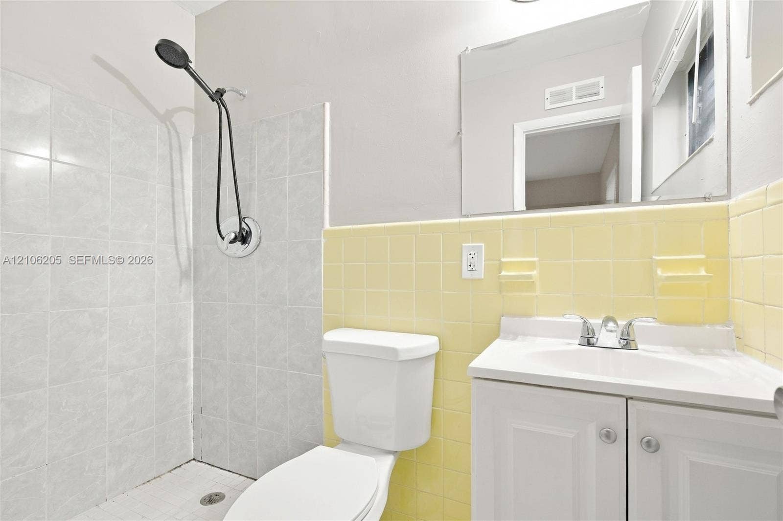 6941 SW 5th Street, Pembroke Pines, Pembroke Pines, FL 33023 Bathroom featuring a white vanity cabinet, ceramic tile walls, a wall-mounted mirror, and a shower head with an adjustable hose