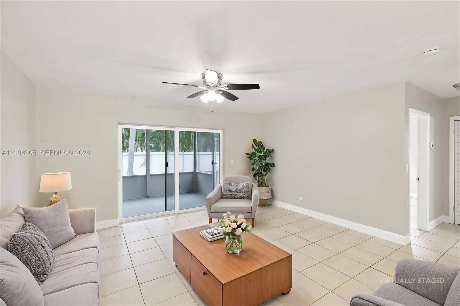 6941 SW 5th Street, Pembroke Pines, Pembroke Pines, FL 33023 Spacious room featuring neutral tile flooring, a multi-blade ceiling fan with integrated lighting, and sliding glass doors opening to an enclosed patio area