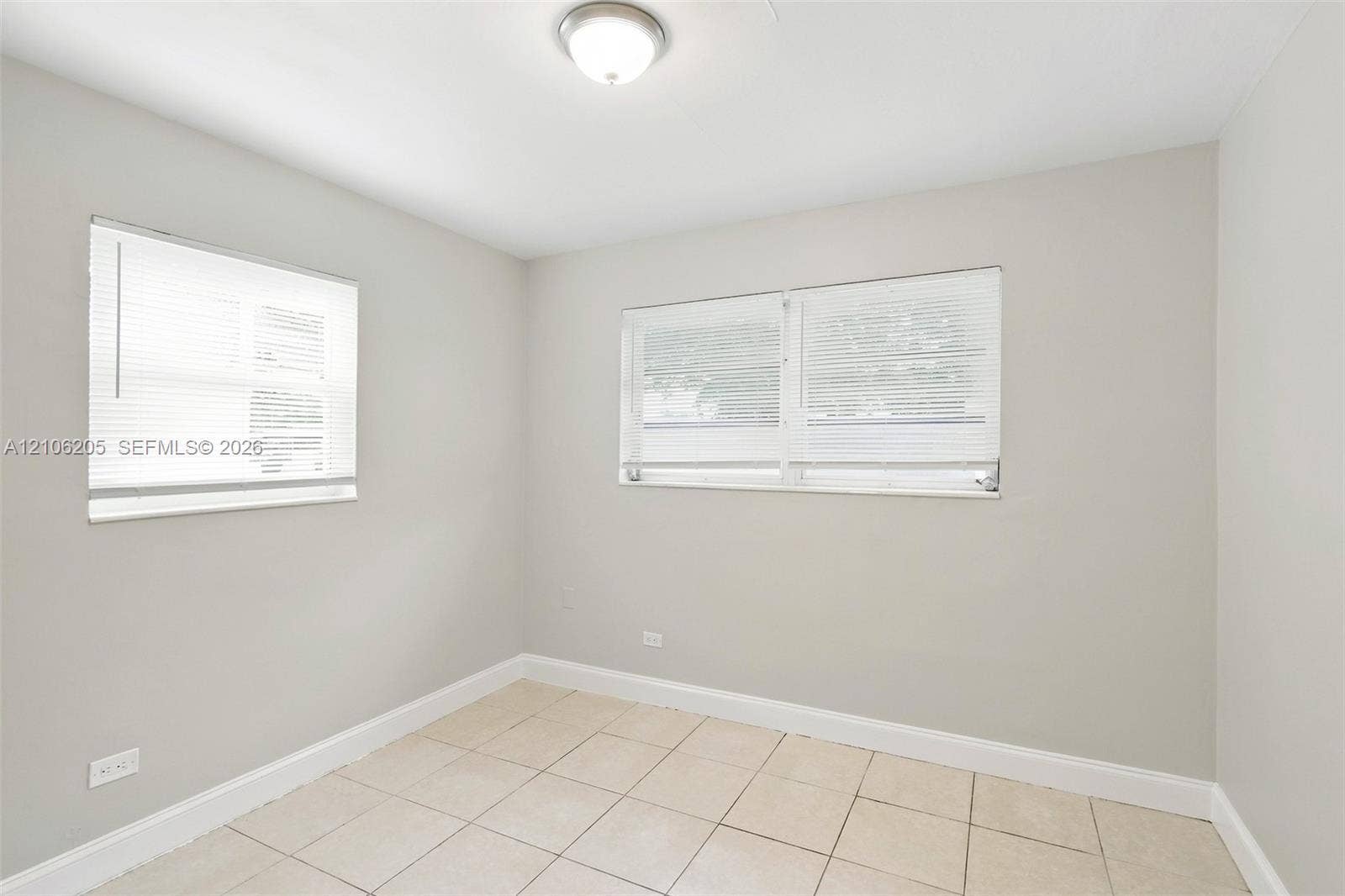 6941 SW 5th Street, Pembroke Pines, Pembroke Pines, FL 33023 Neutral-toned walls, square tile flooring, two multi-pane windows with horizontal blinds, and a central ceiling-mounted light fixture
