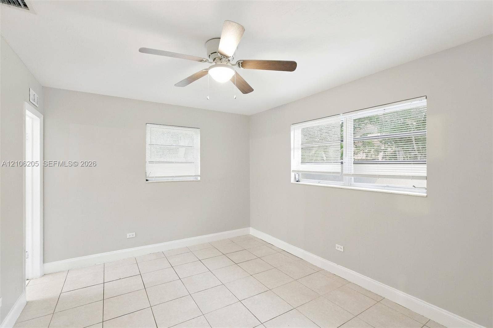 6941 SW 5th Street, Pembroke Pines, Pembroke Pines, FL 33023 Neutral-toned interior featuring large-format tile flooring, a multi-blade ceiling fan with integrated lighting, and dual windows