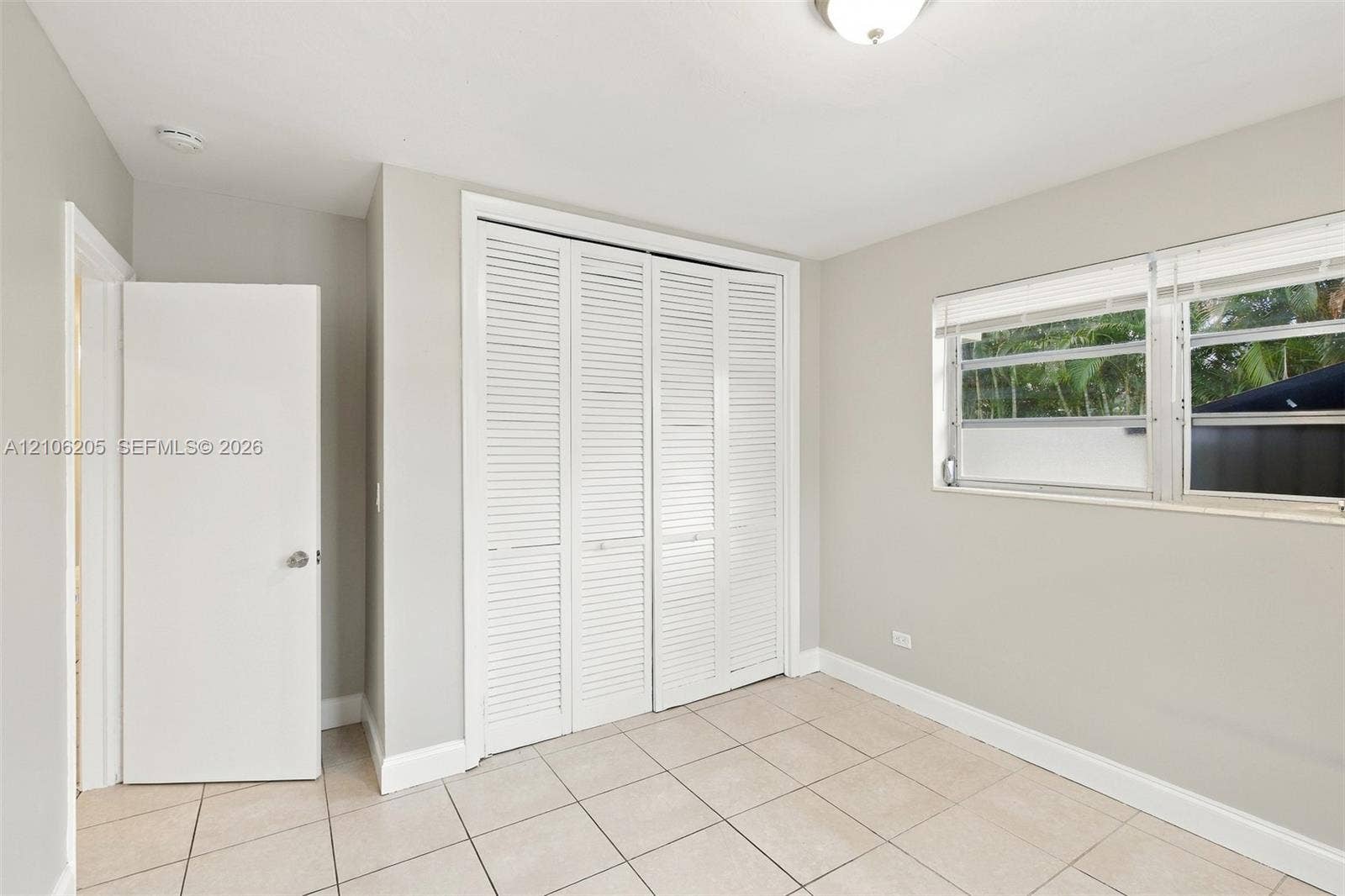6941 SW 5th Street, Pembroke Pines, Pembroke Pines, FL 33023 Room featuring tile flooring, neutral wall paint, white louvered-style bi-fold closet doors, and large windows with horizontal blinds