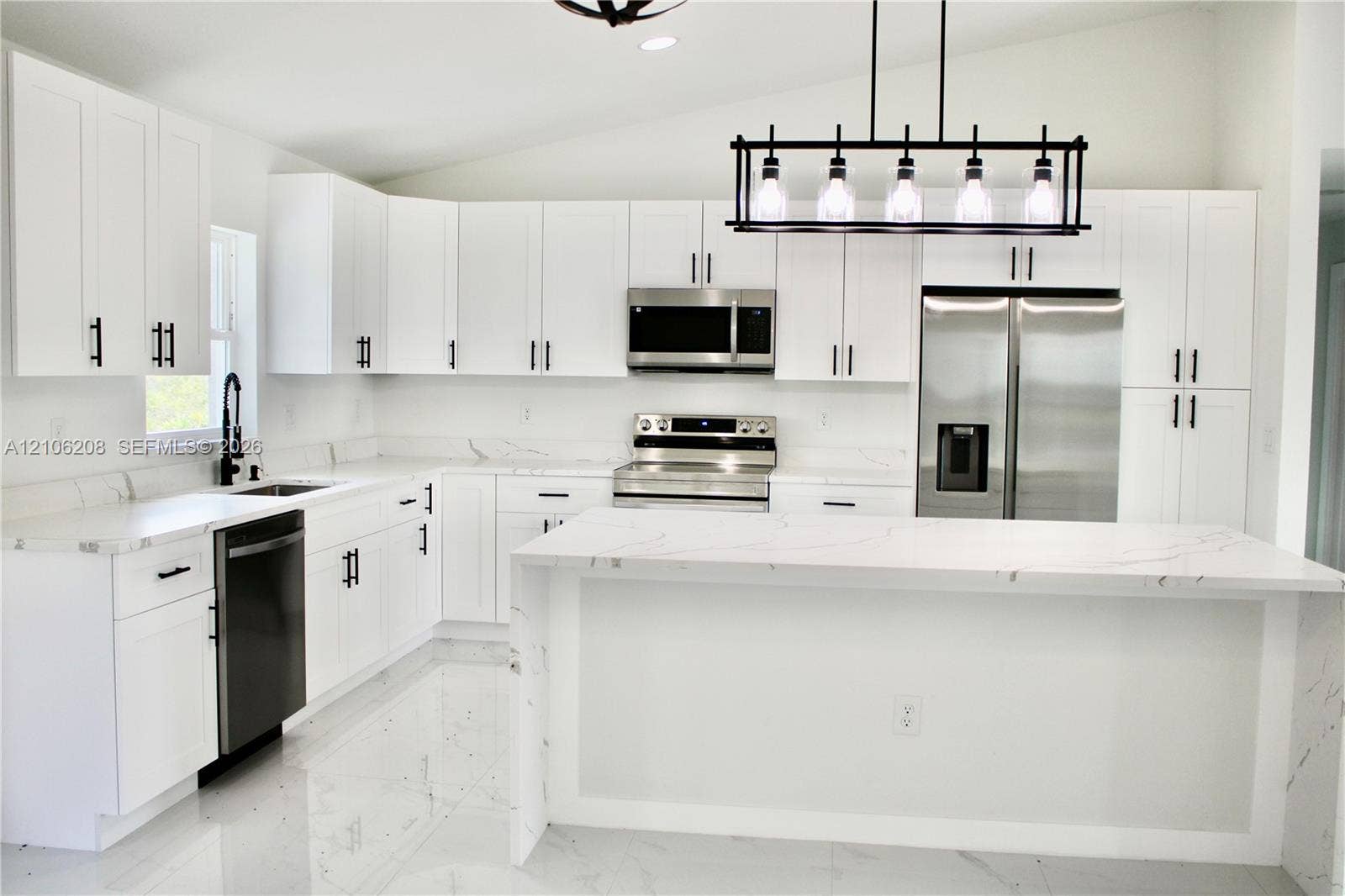 Kitchen featuring white cabinetry with matte black hardware, stone-patterned countertops, a central island, stainless steel appliances, and a linear pendant light fixture