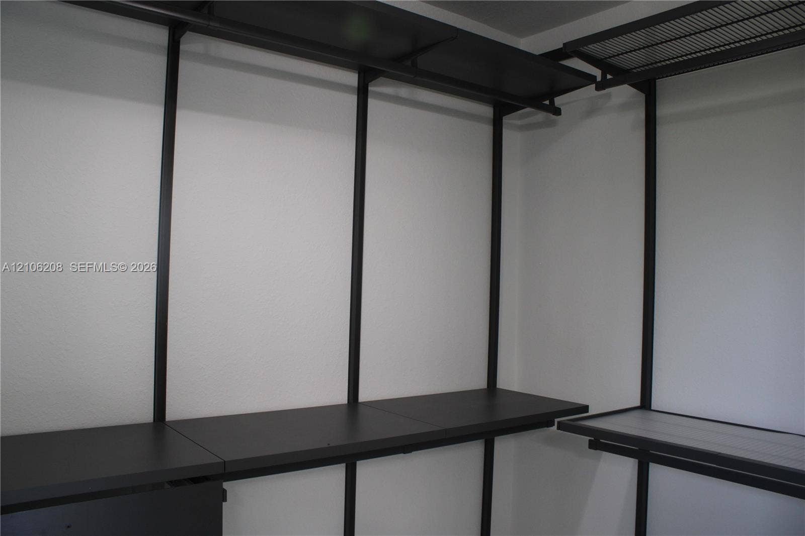 Custom closet organization system featuring black metal framing, tiered shelving, and integrated hanging rods