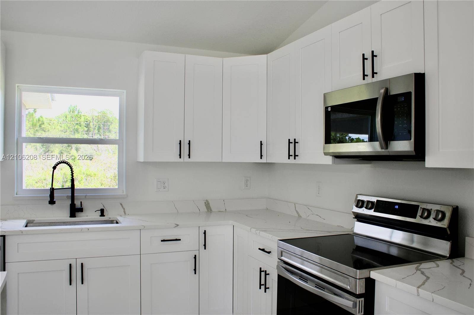Kitchen featuring white Shaker-style cabinetry, stone-patterned countertops, stainless steel appliances, and a high-arch matte black faucet