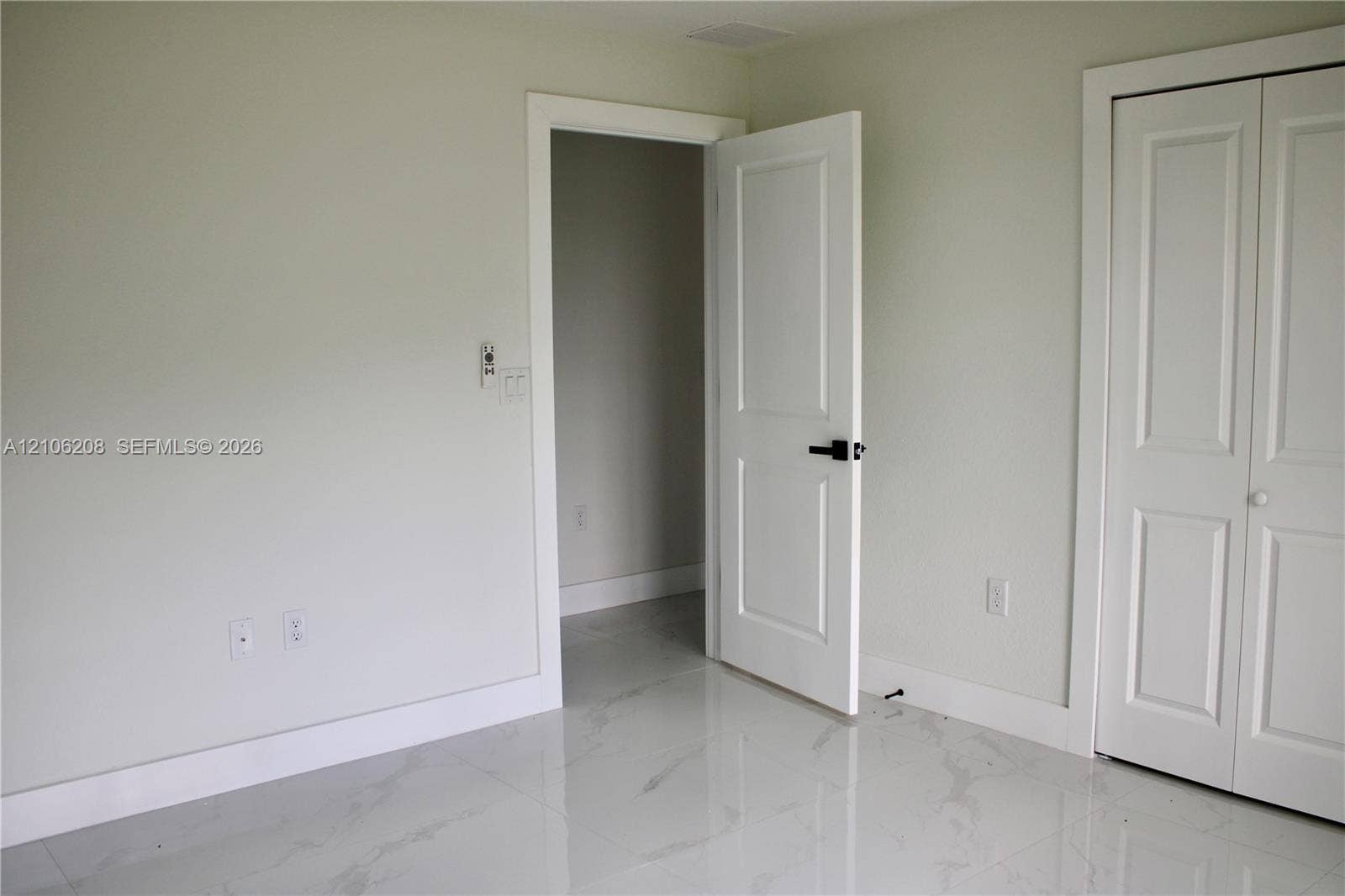 Interior room featuring polished stone-finish tile flooring, white two-panel interior doors, and matte black hardware