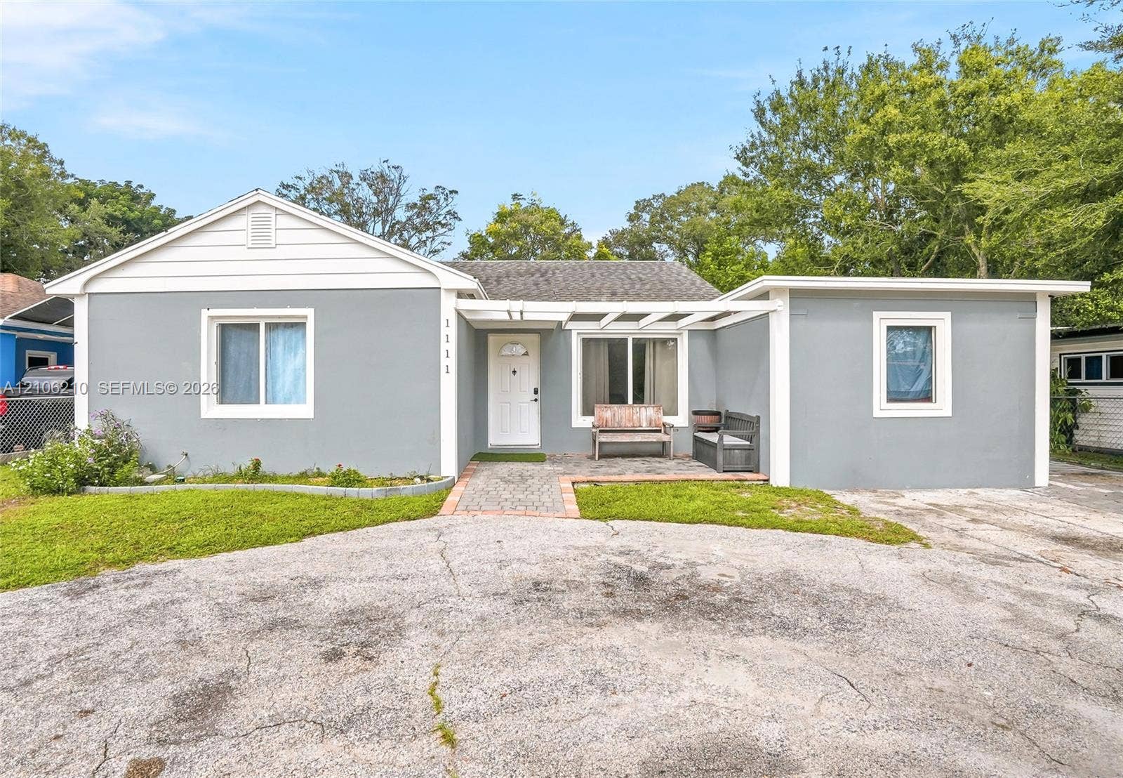 1111 S 7th Street, Fort Pierce, FL 34950 Single-story exterior featuring a gray stucco facade, white trim, a covered patio area with a wooden pergola, and a stone-paved walkway