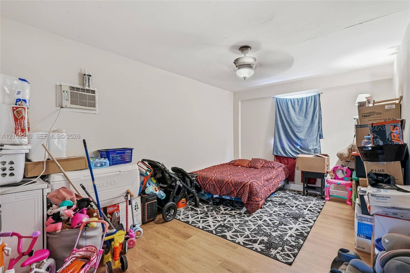 1111 S 7th Street, Fort Pierce, FL 34950 Interior room featuring light wood-finish flooring, a ceiling fan with integrated lighting, and a wall-mounted air conditioning unit
