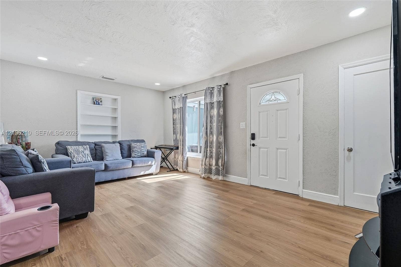 1111 S 7th Street, Fort Pierce, FL 34950 Living area featuring wood-finish flooring, recessed lighting, built-in wall shelving, and a paneled entry door with decorative glass insert