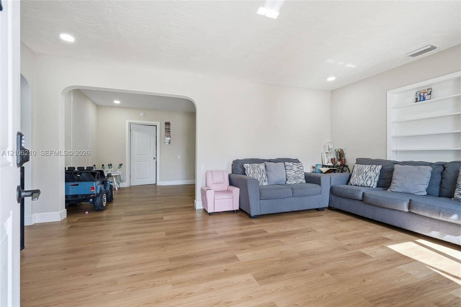 1111 S 7th Street, Fort Pierce, FL 34950 Living area featuring wood-finish flooring, recessed lighting, arched wall opening, and built-in white shelving