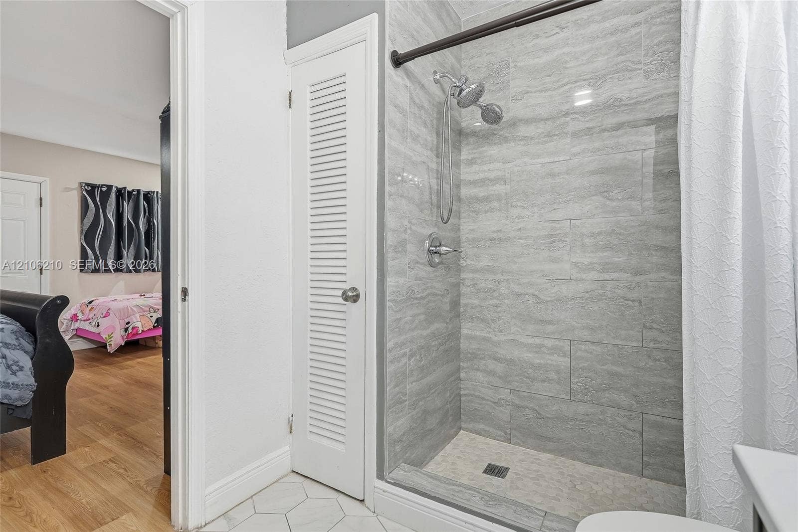 1111 S 7th Street, Fort Pierce, FL 34950 Walk-in shower with grey horizontal tile surround, handheld shower head, and built-in closet with white louvered door