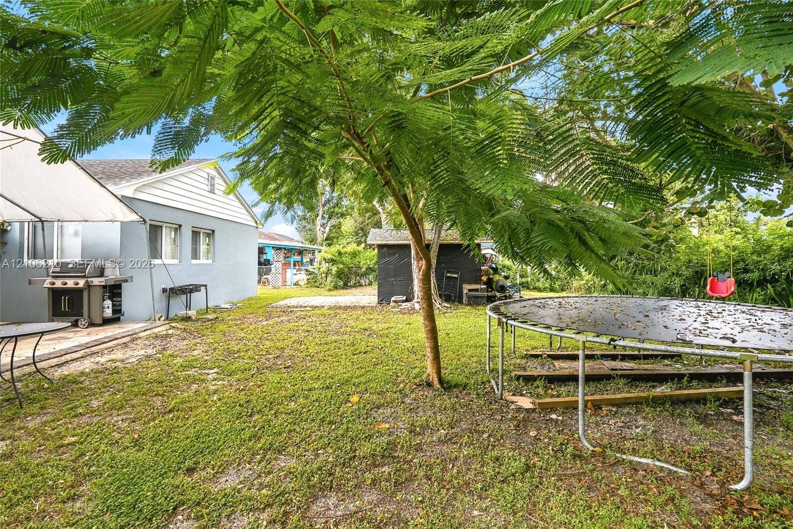 1111 S 7th Street, Fort Pierce, FL 34950 Exterior grounds featuring a concrete patio, mature landscaping, and a detached structure