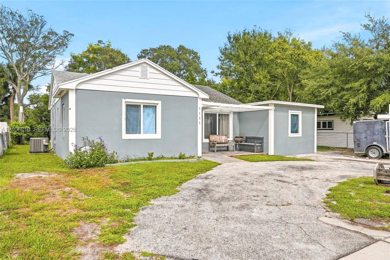 1111 S 7th Street, Fort Pierce, FL 34950 Exterior featuring a painted stucco facade, gable roofline, covered porch area, and an expansive asphalt driveway