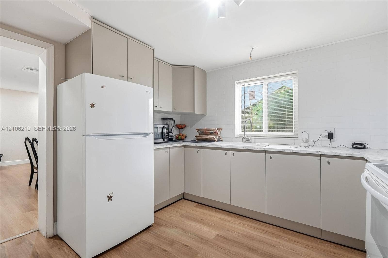 1111 S 7th Street, Fort Pierce, FL 34950 Kitchen featuring flat-panel cabinetry, stone-finish countertops, subway tile backsplash, stainless steel sink with gooseneck faucet, and wood-finish flooring
