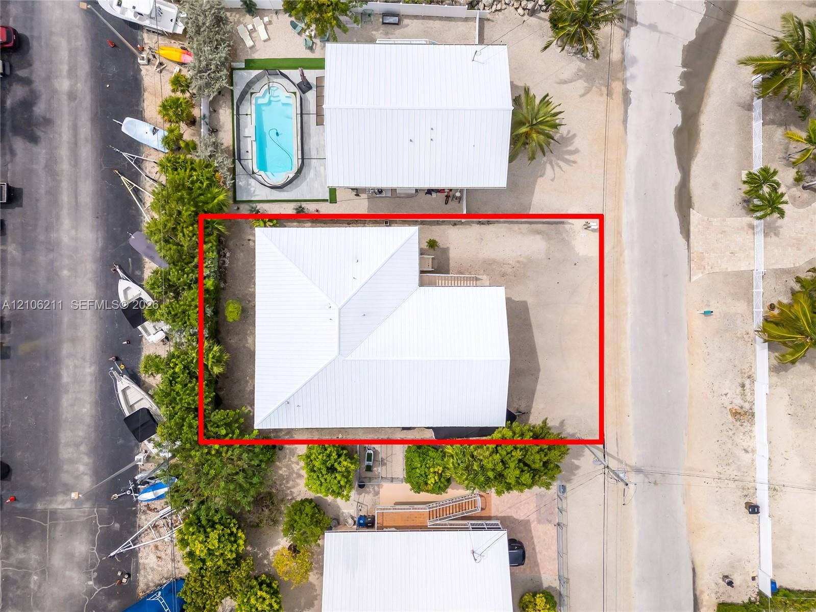 Aerial perspective of property featuring a metal roof and mature tropical landscaping
