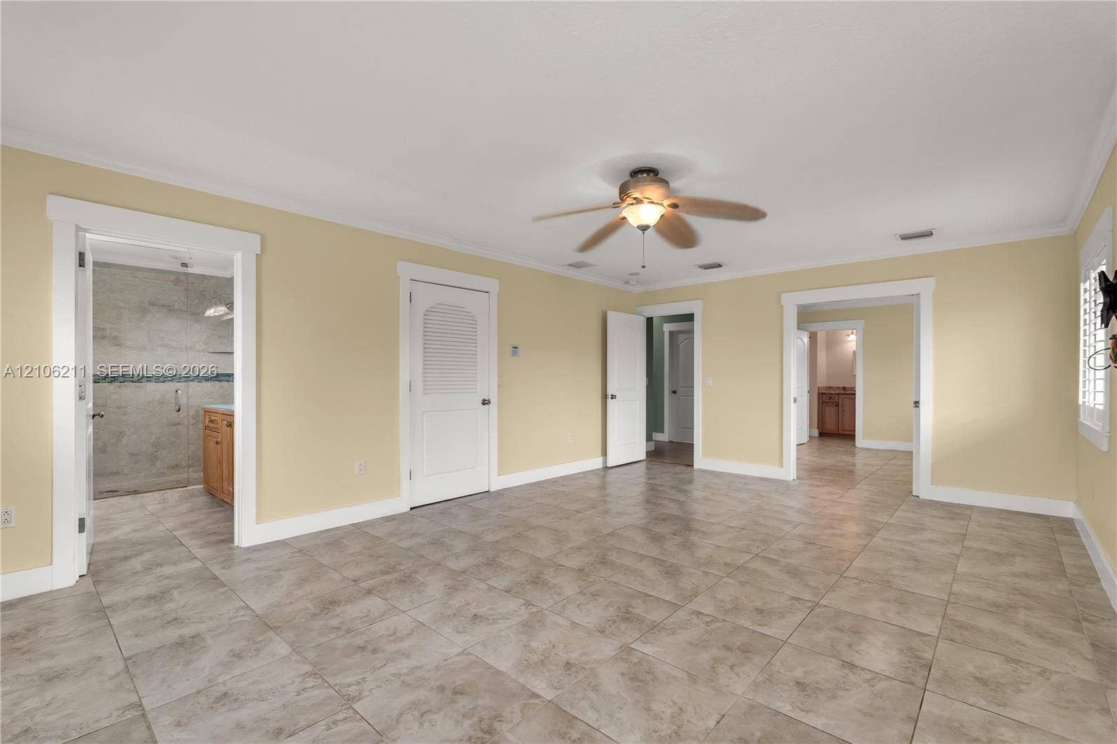 Spacious room featuring tile flooring, a central ceiling fan with integrated lighting, recessed lighting, and multiple arched door frames
