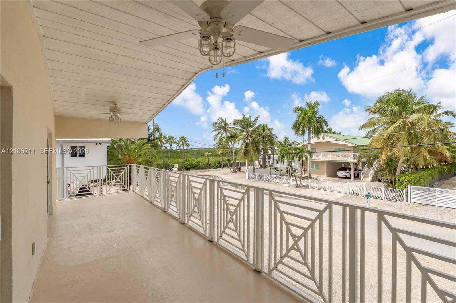 Covered balcony featuring concrete flooring, geometric metal railing, and dual ceiling fans