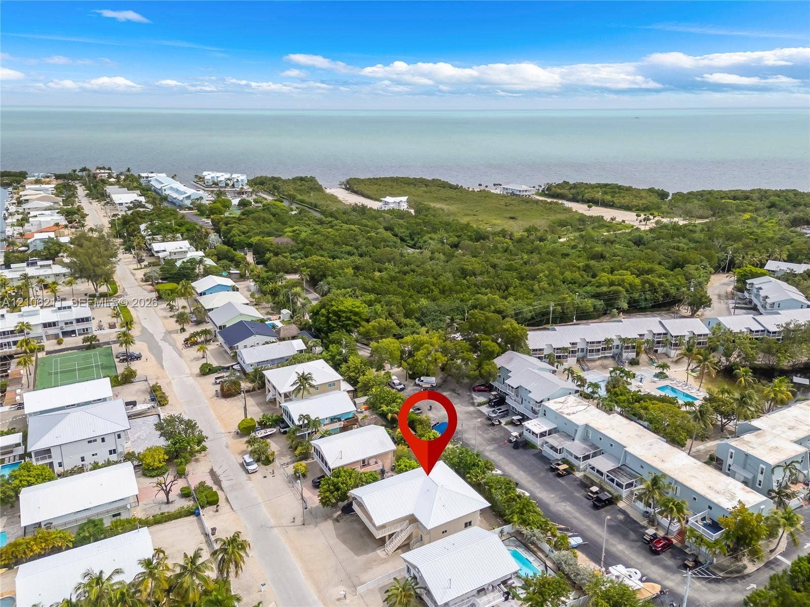 Aerial perspective of coastal residential property featuring a metal roof, elevated structure, and proximity to the coastline