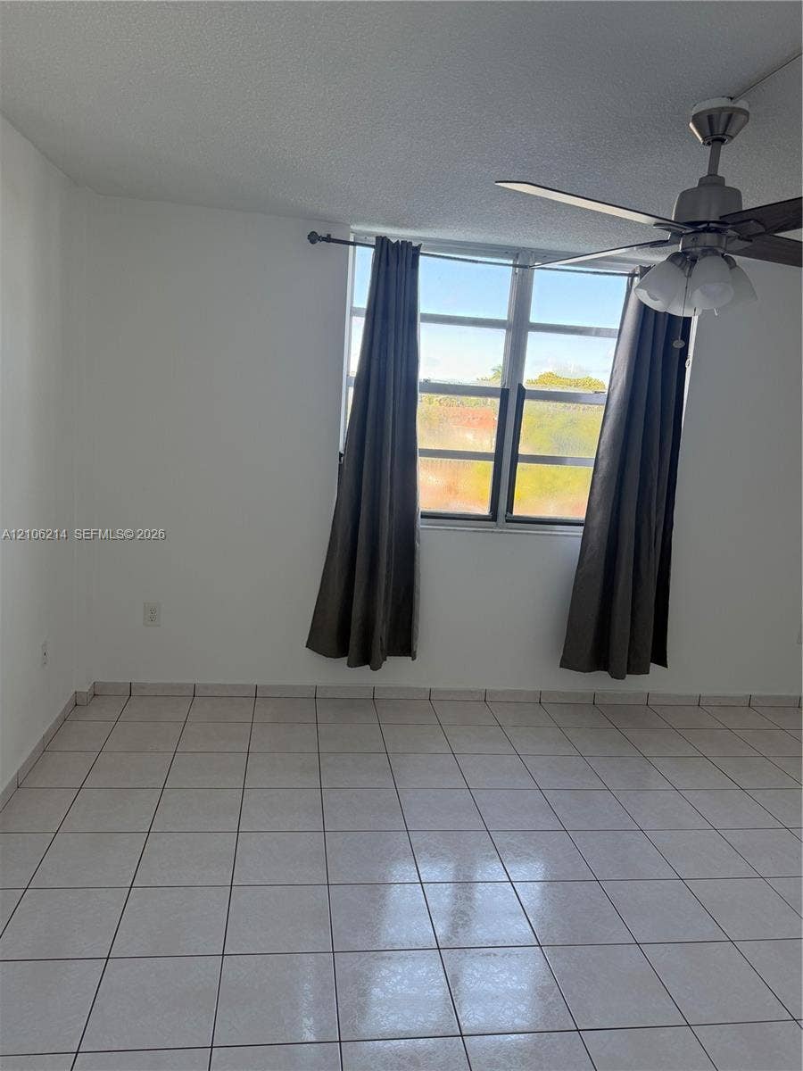 2841 NE 163rd Street, #305, North Miami Beach, North Miami Beach, FL 33160 Neutral-toned room featuring large-format ceramic tile flooring, multi-pane window, and a multi-light ceiling fan