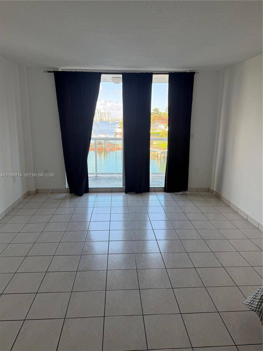2841 NE 163rd Street, #305, North Miami Beach, North Miami Beach, FL 33160 Interior space featuring ceramic tile flooring, floor-to-ceiling glass sliding doors, and a private balcony overlooking the water