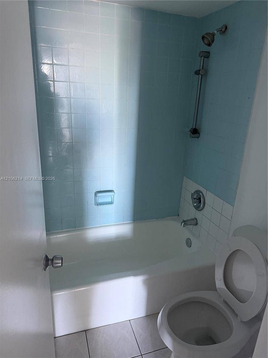 2841 NE 163rd Street, #305, North Miami Beach, North Miami Beach, FL 33160 Full bathroom featuring a tub-shower combination with light blue tile surround, adjustable shower head on a sliding bar, and tile flooring
