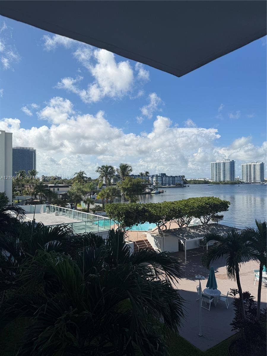 2841 NE 163rd Street, #305, North Miami Beach, North Miami Beach, FL 33160 Elevated exterior perspective featuring a swimming pool, paved sundeck, pergola-covered seating area, and waterfront access