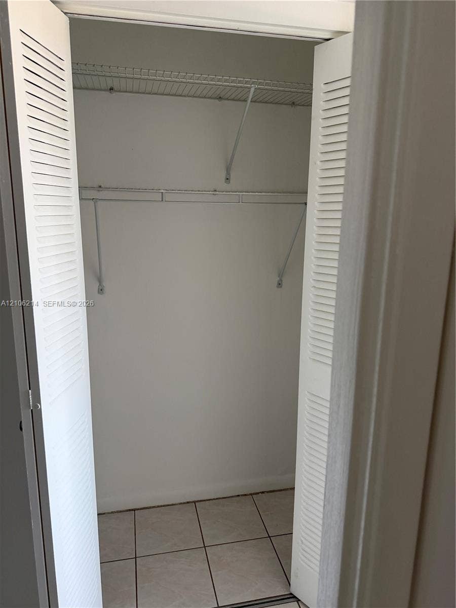 2841 NE 163rd Street, #305, North Miami Beach, North Miami Beach, FL 33160 Closet featuring white louvered bifold doors, tile flooring, and built-in wire shelving
