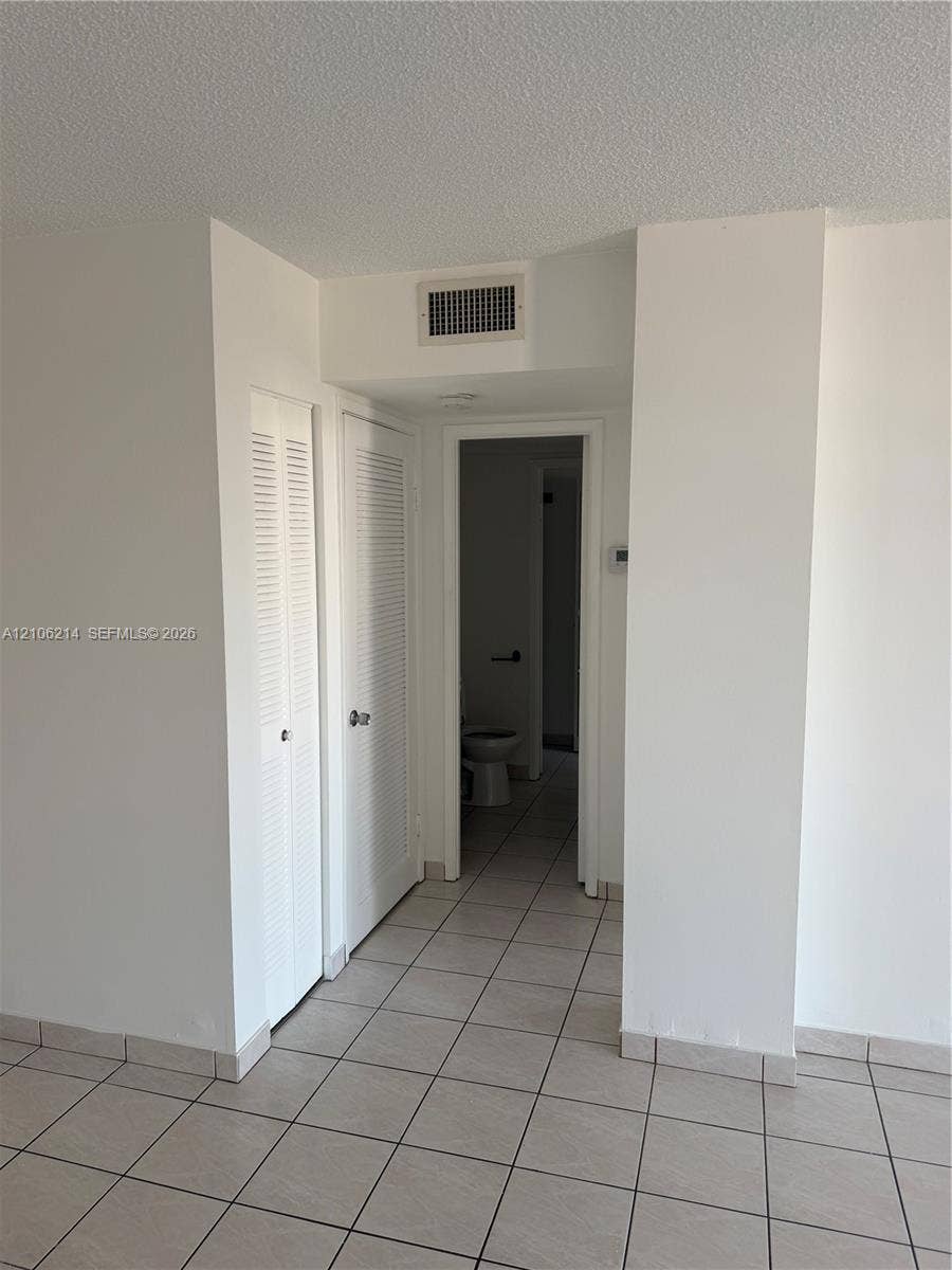 2841 NE 163rd Street, #305, North Miami Beach, North Miami Beach, FL 33160 Interior space featuring neutral tile flooring and two sets of louvered-style closet doors