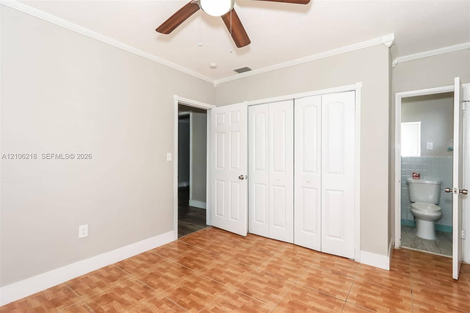 Room featuring wood-finish flooring, a ceiling fan with integrated lighting, multi-panel closet doors, and crown molding