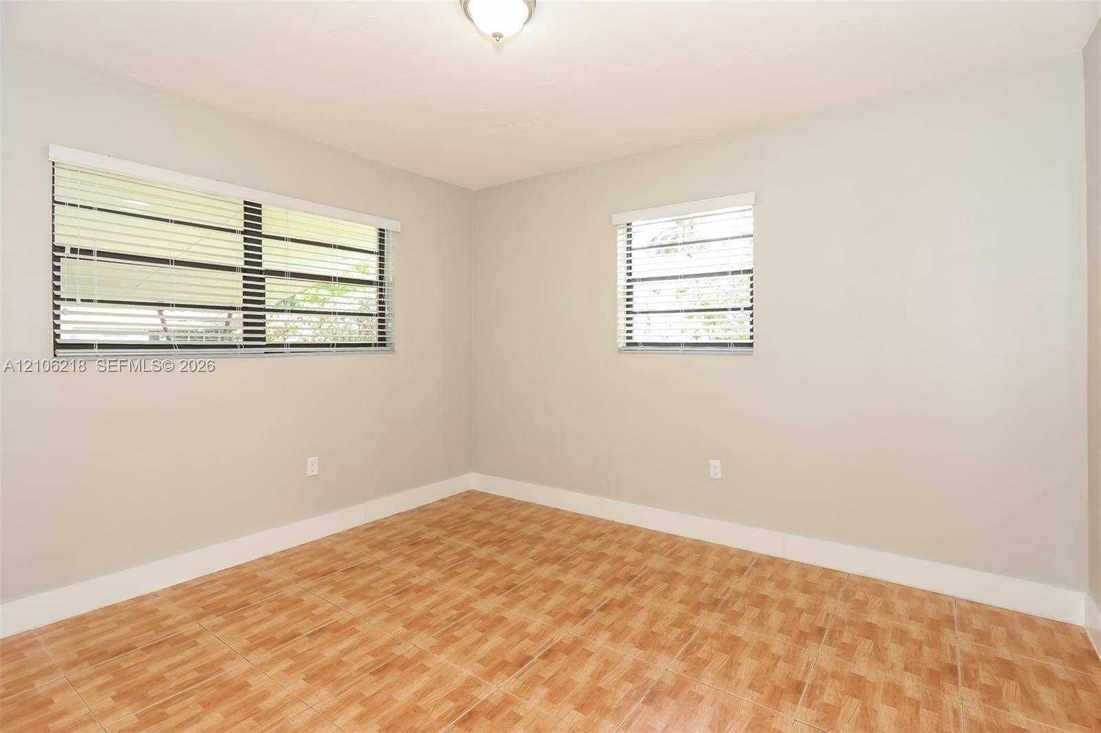 Neutral-toned interior walls, ceramic tile flooring, and dual windows equipped with horizontal blinds
