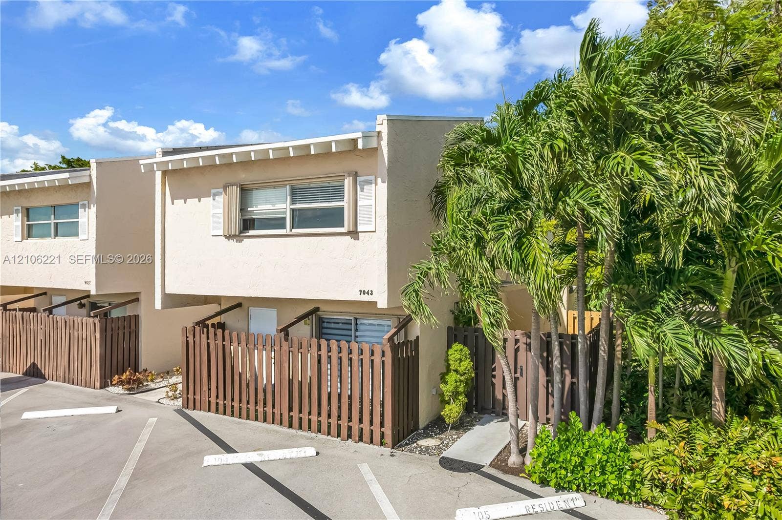 Stucco exterior residence featuring a shed roofline, horizontal sliding windows, and a privacy wood fence enclosing a ground-level patio