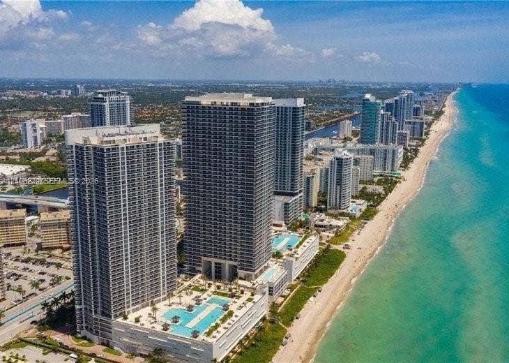 High-rise coastal property featuring direct oceanfront access, elevated swimming pools, expansive sun decks, and panoramic water horizons