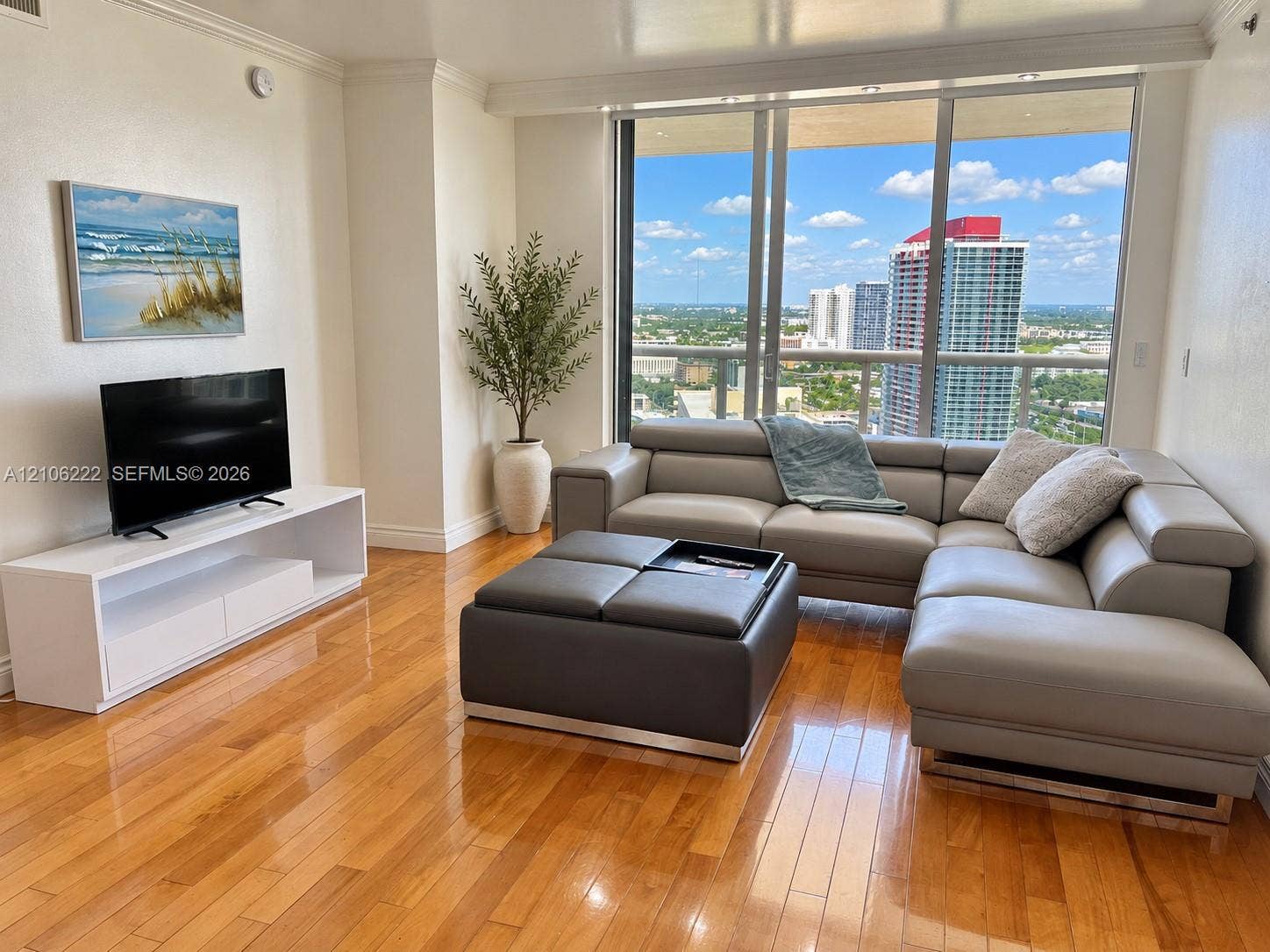 Living space featuring polished wood-finish flooring, floor-to-ceiling windows, and a private balcony