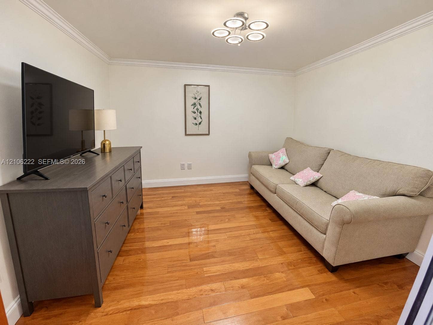 Bedroom/Den/office space featuring wood-finish flooring, crown molding, and a contemporary five-light circular ceiling fixture