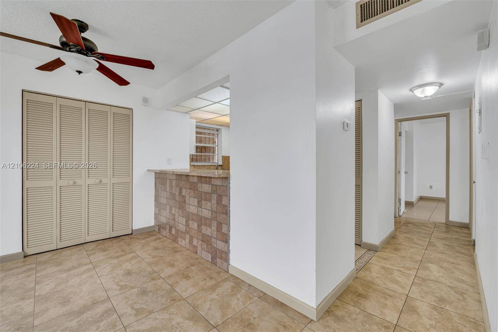 8887 Fontainebleau Boulevard, #206, Miami, Miami, FL 33172 Tile flooring, pass-through counter with tiled facade, ceiling fan with light fixture, and floor-to-ceiling louvered closet doors